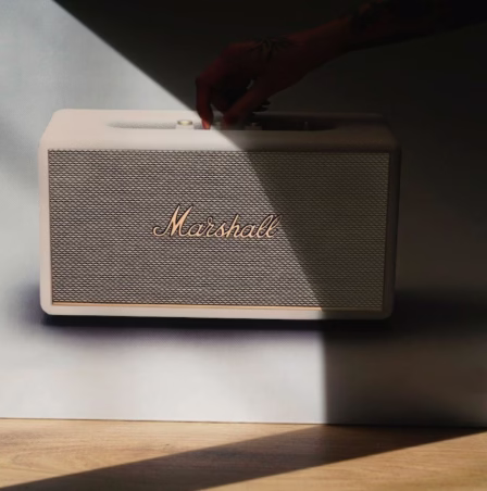 Рука перемикає латунні регулятори на панелі колонки Marshall Stanmore III Cream
